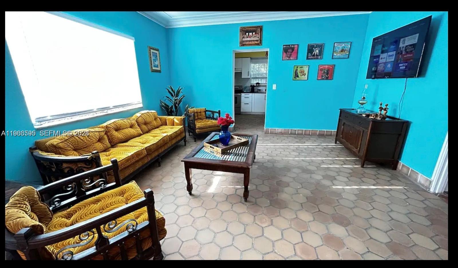 A living room features bright blue walls, yellow velvet furniture, and hexagonal floor tiles — 843 NW 3rd St # 1, Miami FL 33128, MIAMI, FL