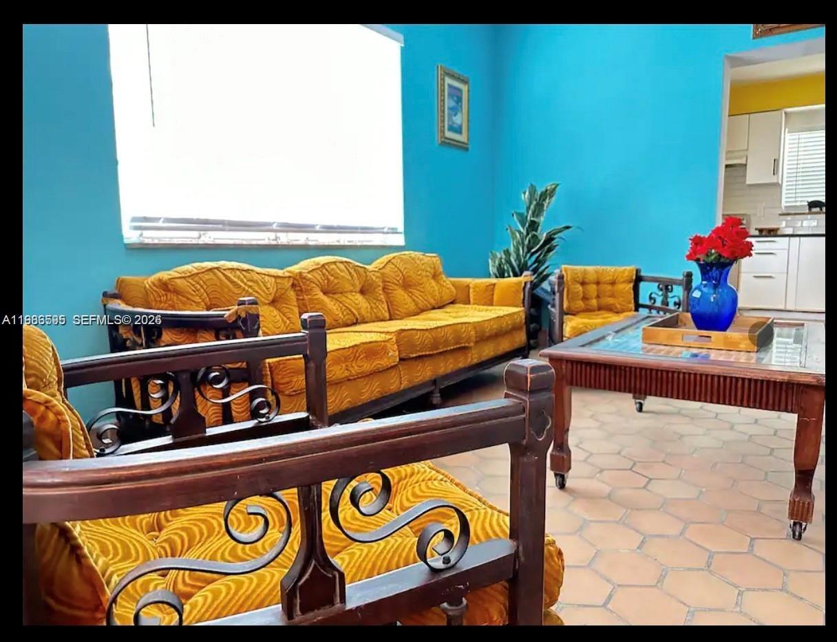 A living room features bright blue walls, yellow tufted furniture, and light-colored tile flooring — 843 NW 3rd St # 1, Miami FL 33128, MIAMI, FL