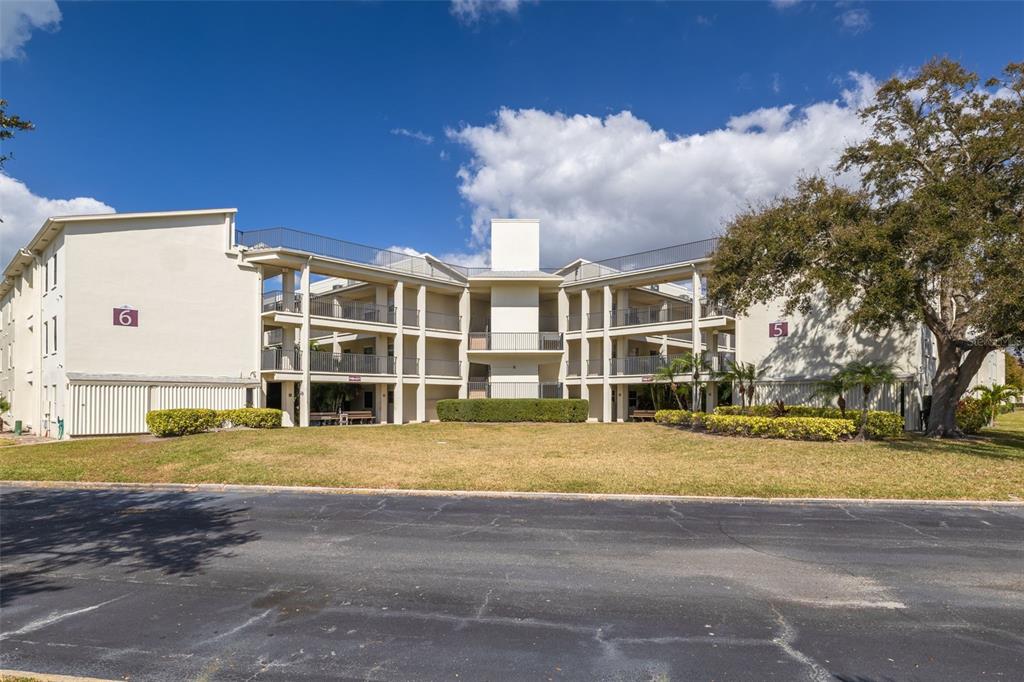 A three-story apartment building with beige exterior walls and open-air walkways — 2700 BAYSHORE BOULEVARD UNIT 5302, DUNEDIN, FL