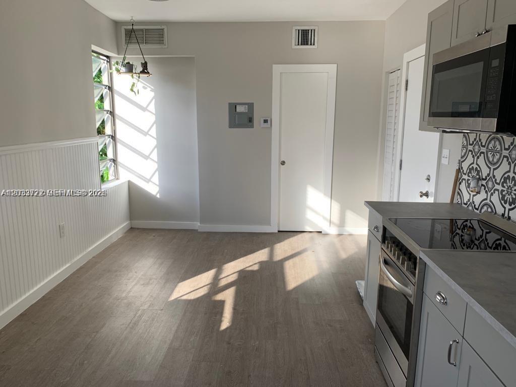 A kitchen with light wood-look flooring, gray cabinets, a stainless steel stove, and a window — 2932 NW 16th Ave # 3A, Miami FL 33142, MIAMI, FL