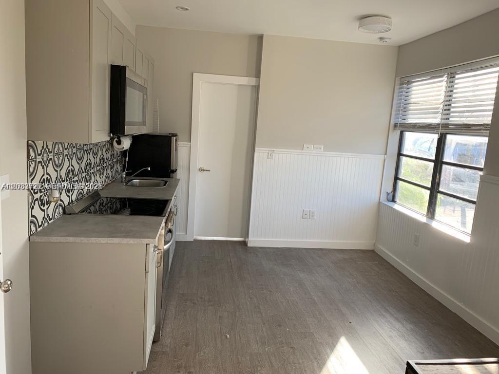 A kitchen features gray cabinets, a patterned tile backsplash, and a window with blinds — 2932 NW 16th Ave # 3A, Miami FL 33142, MIAMI, FL