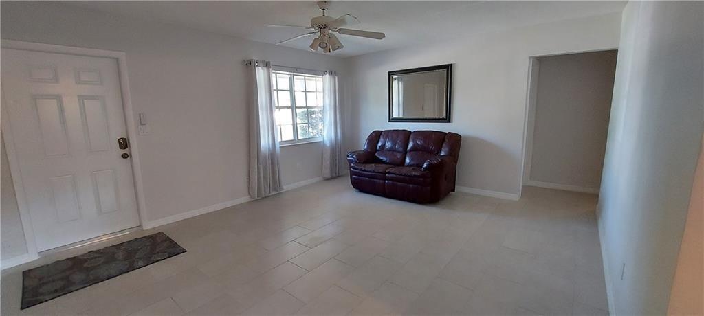 A living room features light tile flooring, a white front door, and a maroon loveseat — 738 SW 5th Avenue, Hallandale Beach FL 33009, HALLANDALE BEACH, FL