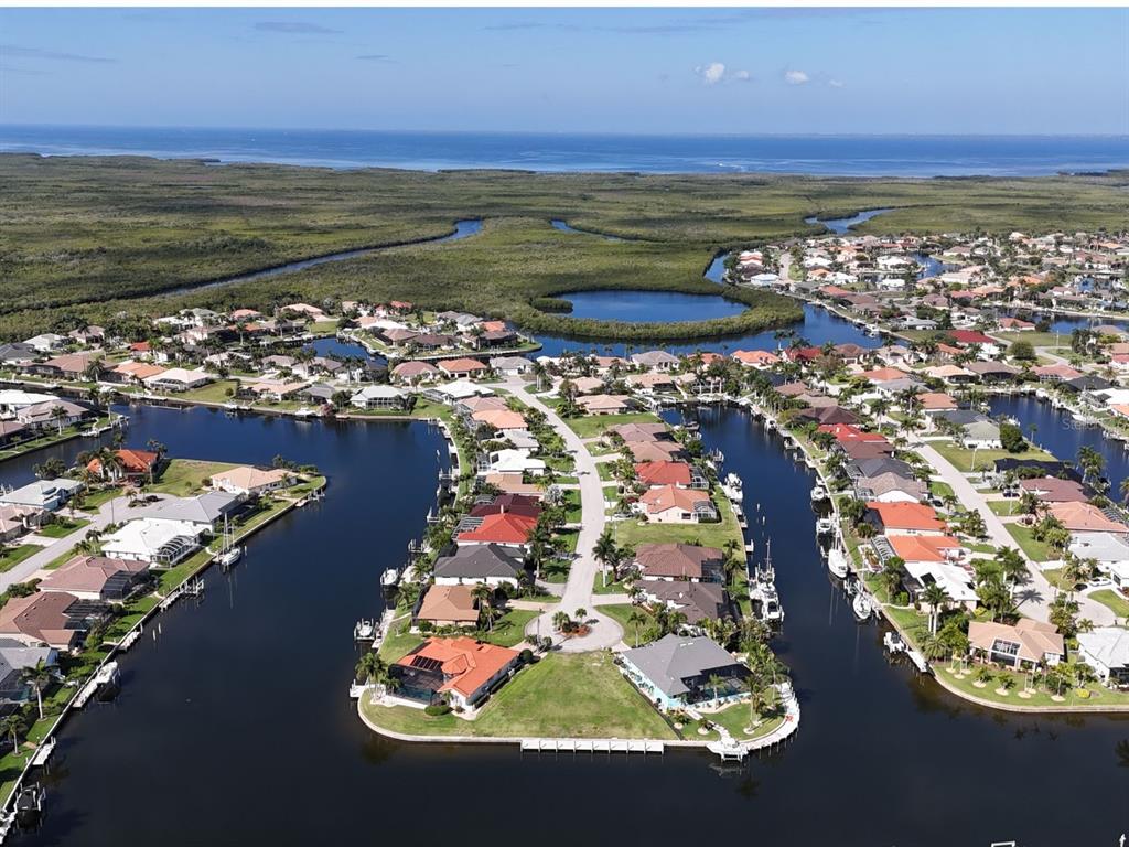 An aerial view shows waterfront homes with boat docks along canals near a mangrove forest — 402 VALLETTA COURT, PUNTA GORDA, FL