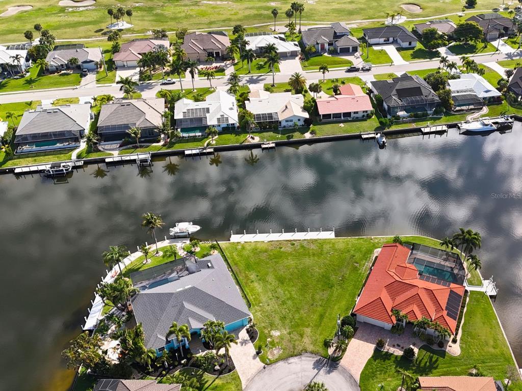 An aerial view shows waterfront homes with pools and docks along a canal — 402 VALLETTA COURT, PUNTA GORDA, FL
