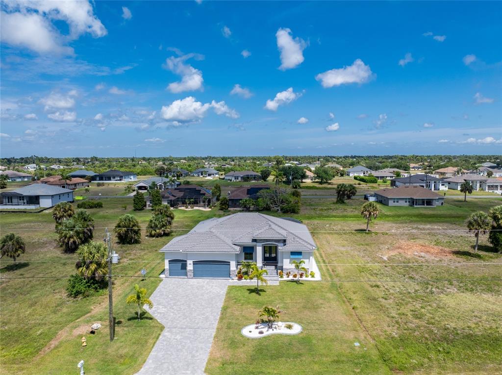 An aerial view of a modern single-story house with a paved driveway and surrounding landscape — 255 ROTONDA BOULEVARD S, ROTONDA WEST, FL