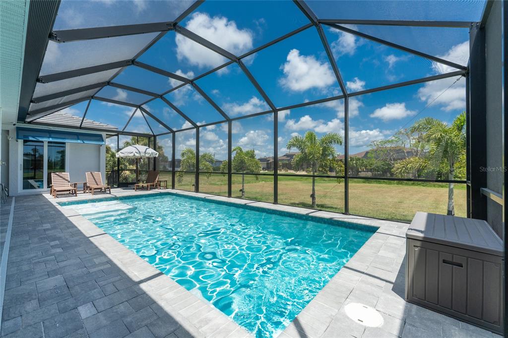 A screened-in swimming pool with a paver deck and a view of a grassy yard — 255 ROTONDA BOULEVARD S, ROTONDA WEST, FL