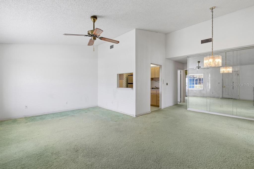A living room features green wall-to-wall carpeting, a ceiling fan, and mirrored closet doors — 33 SANDRA CIRCLE, NEW SMYRNA BEACH, FL