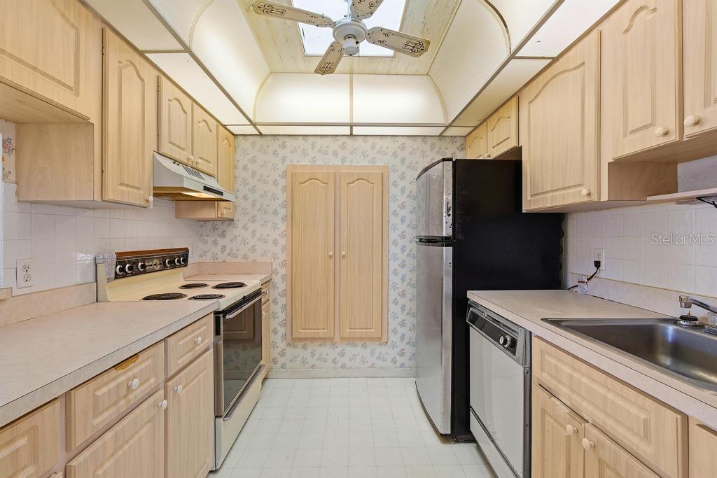A kitchen with light wood cabinets, floral wallpaper, a ceiling fan, and white appliances — 33 SANDRA CIRCLE, NEW SMYRNA BEACH, FL