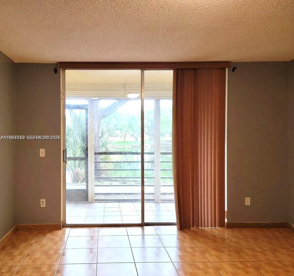 A room with tile flooring and a sliding glass door leading to a screened balcony — 3253 Foxcroft Rd # G107, Miramar FL 33025, MIRAMAR, FL
