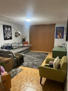 A living room features a grey sofa, a green armchair, and a large area rug — 3253 Foxcroft Rd # G107, Miramar FL 33025, MIRAMAR, FL