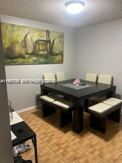 A dining room features a square dark wood table with benches and a large pear painting — 3253 Foxcroft Rd # G107, Miramar FL 33025, MIRAMAR, FL