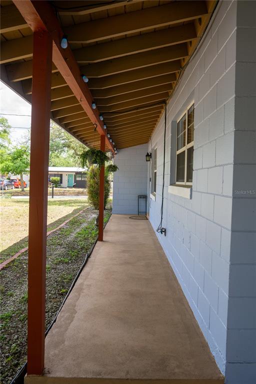 A covered concrete porch runs along the side of a light blue concrete block house — 5350 INCA STREET, ORLANDO, FL