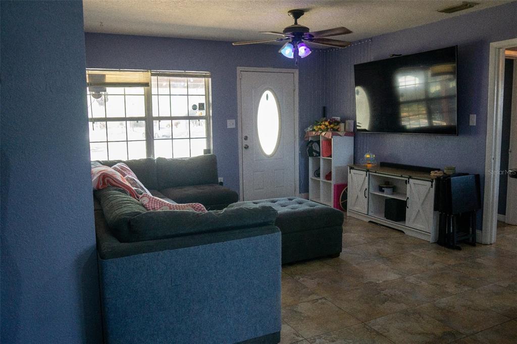 A living room features a sectional sofa, a wall-mounted television, and tile flooring — 5350 INCA STREET, ORLANDO, FL