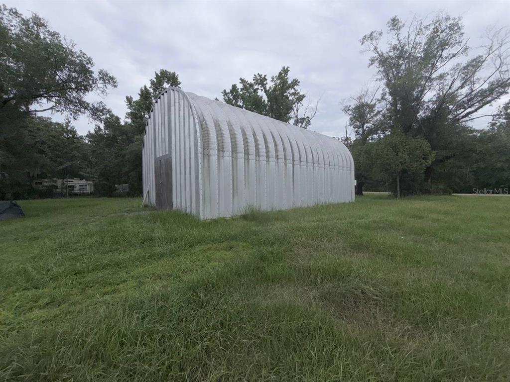 A metal Quonset hut stands in a grassy field surrounded by trees — 10600 W DEEP CREEK BOULEVARD, HASTINGS, FL