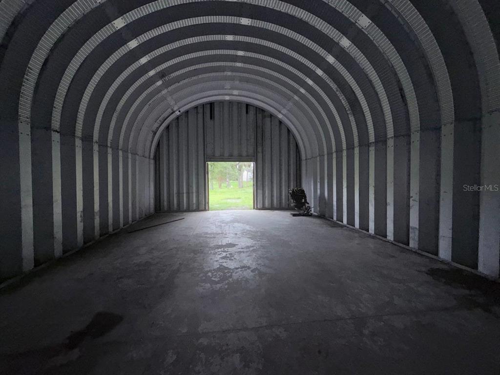 An interior view of a metal Quonset hut with a concrete floor and arched ceiling — 10600 W DEEP CREEK BOULEVARD, HASTINGS, FL