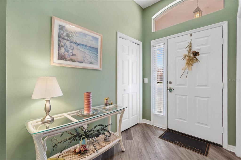 An entryway features a glass-topped console table, light green walls, and a white front door — 1516 MARTINEZ DRIVE, LADY LAKE, FL