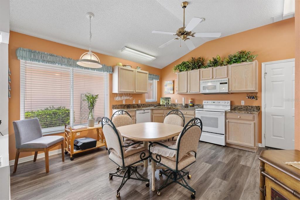 A kitchen with light wood cabinets, orange walls, and a dining table in the center — 1516 MARTINEZ DRIVE, LADY LAKE, FL