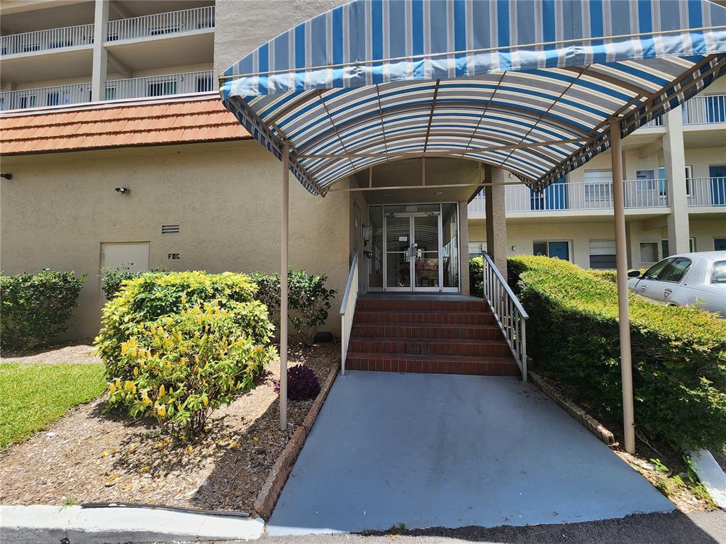 A blue and white striped awning covers the entrance steps to a multi-story apartment building — 1650 1ST AVENUE W UNIT 408B, BRADENTON, FL