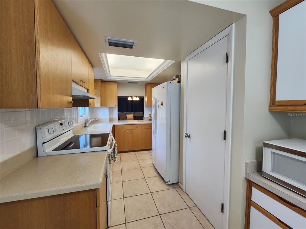 A kitchen features light wood cabinets, white appliances, tile flooring, and a skylight — 1650 1ST AVENUE W UNIT 408B, BRADENTON, FL