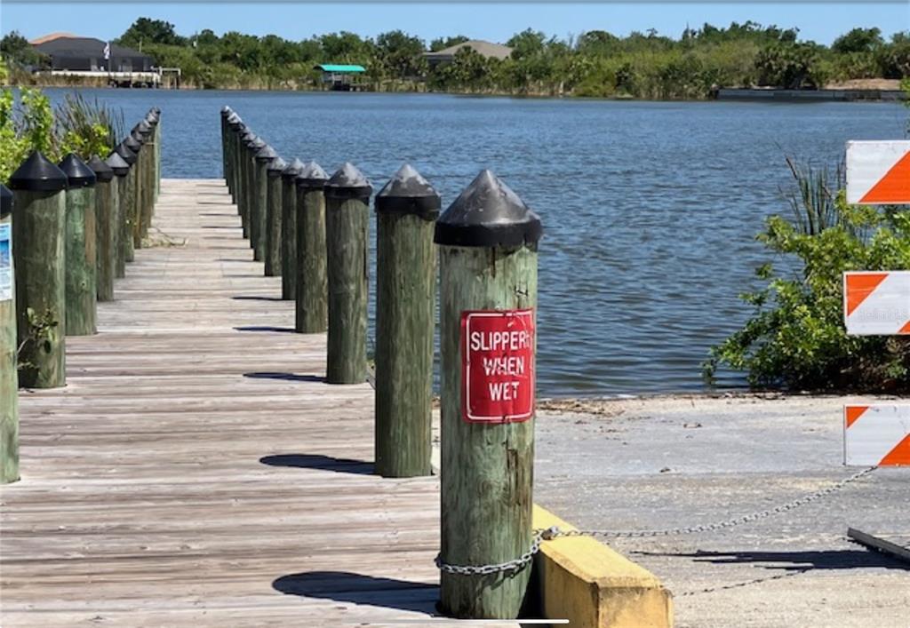 A wooden pier with a row of pilings leads toward a body of water — 13232 KITCHENER AVENUE, PORT CHARLOTTE, FL