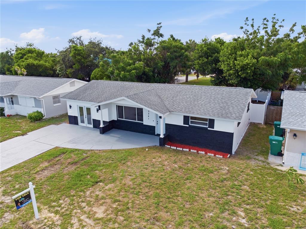 An exterior view of a single-story house with a white and black facade and driveway — 5541 VIOLET DRIVE, NEW PORT RICHEY, FL