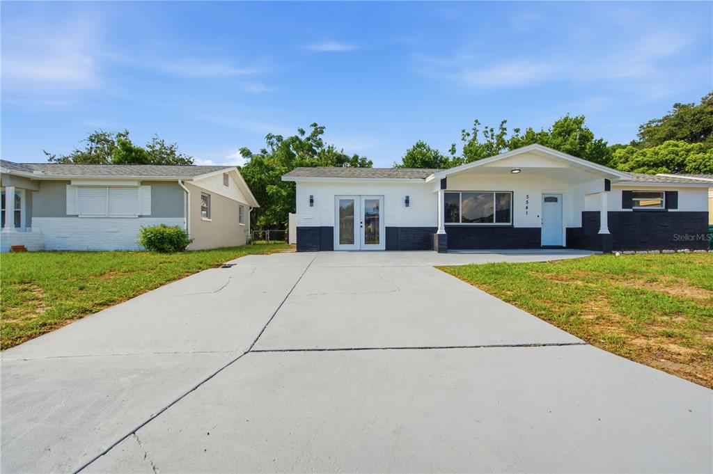 A single-story house with a white and dark gray exterior features a large concrete driveway — 5541 VIOLET DRIVE, NEW PORT RICHEY, FL