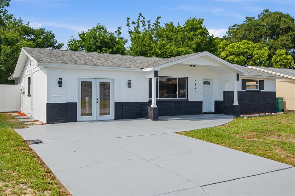 A bright, open-concept living area features white walls, light wood-look flooring, and a modern light — 5541 VIOLET DRIVE, NEW PORT RICHEY, FL