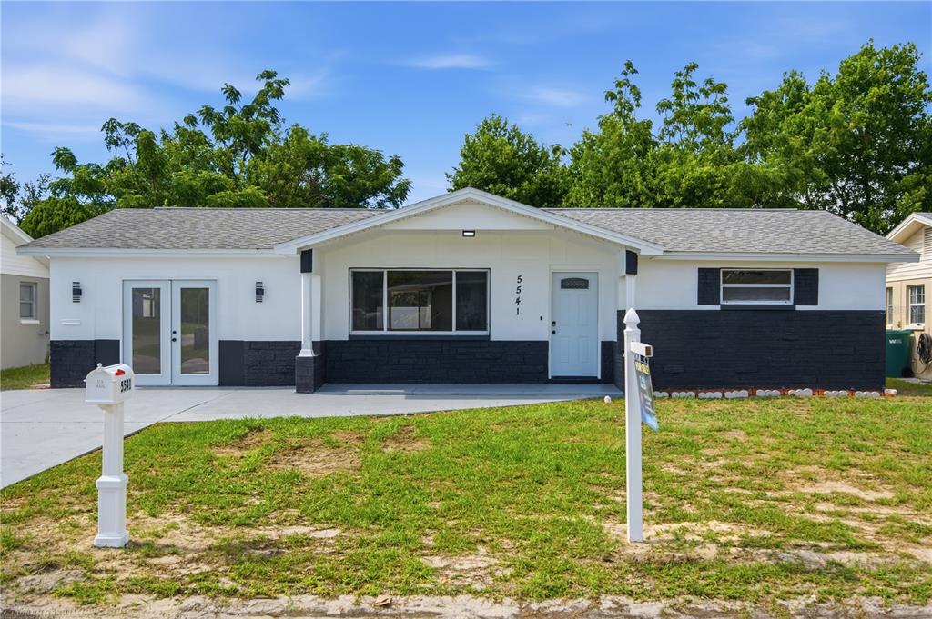 A bright, open-concept living area features white cabinetry, a kitchen island, and light wood flooring — 5541 VIOLET DRIVE, NEW PORT RICHEY, FL
