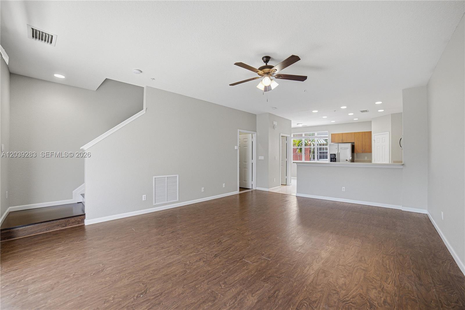 An open-concept living room features wood-look flooring, a ceiling fan, and an adjacent kitchen — 156 Greenwich Cir, Jupiter FL 33458, JUPITER, FL