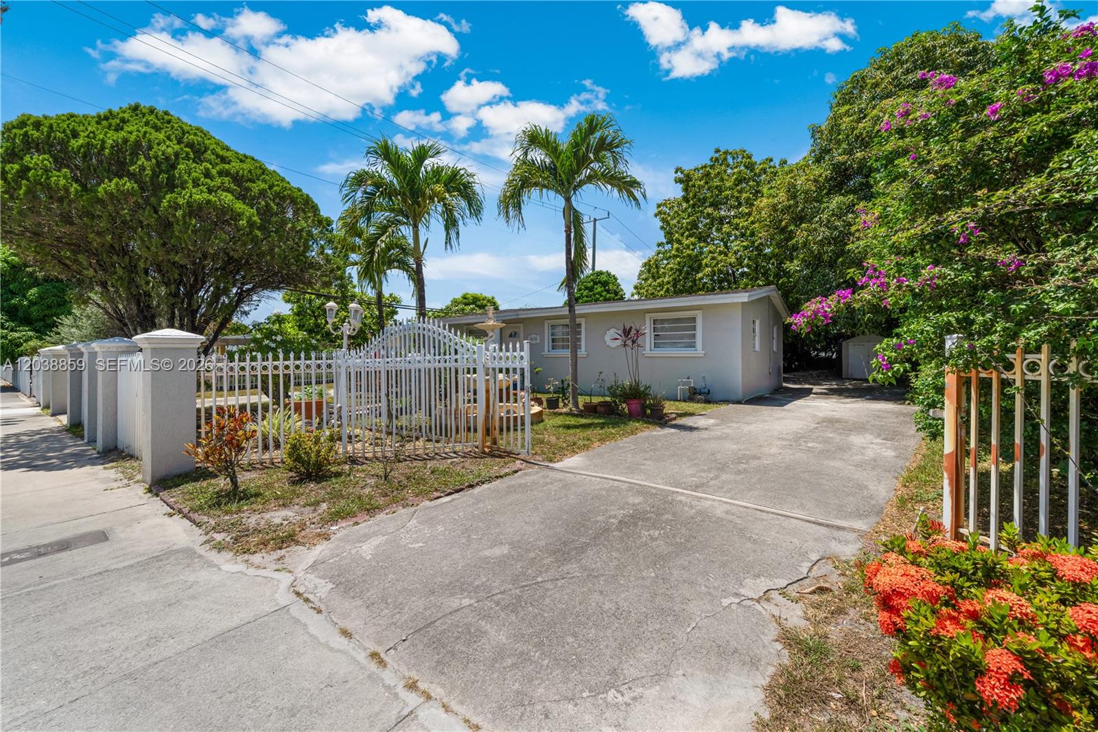 A single-story house with a white fence, concrete driveway, and palm trees in the yard — 3035 NW 83rd St, Miami FL 33147, MIAMI, FL