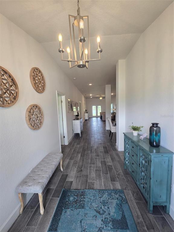 A long entryway features a chandelier, gray tile flooring, a bench, and a blue cabinet — 16215 59TH COURT E, PARRISH, FL