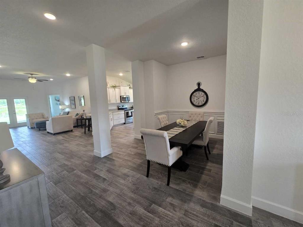 A dining area with a dark table and white chairs sits beside a kitchen — 16215 59TH COURT E, PARRISH, FL