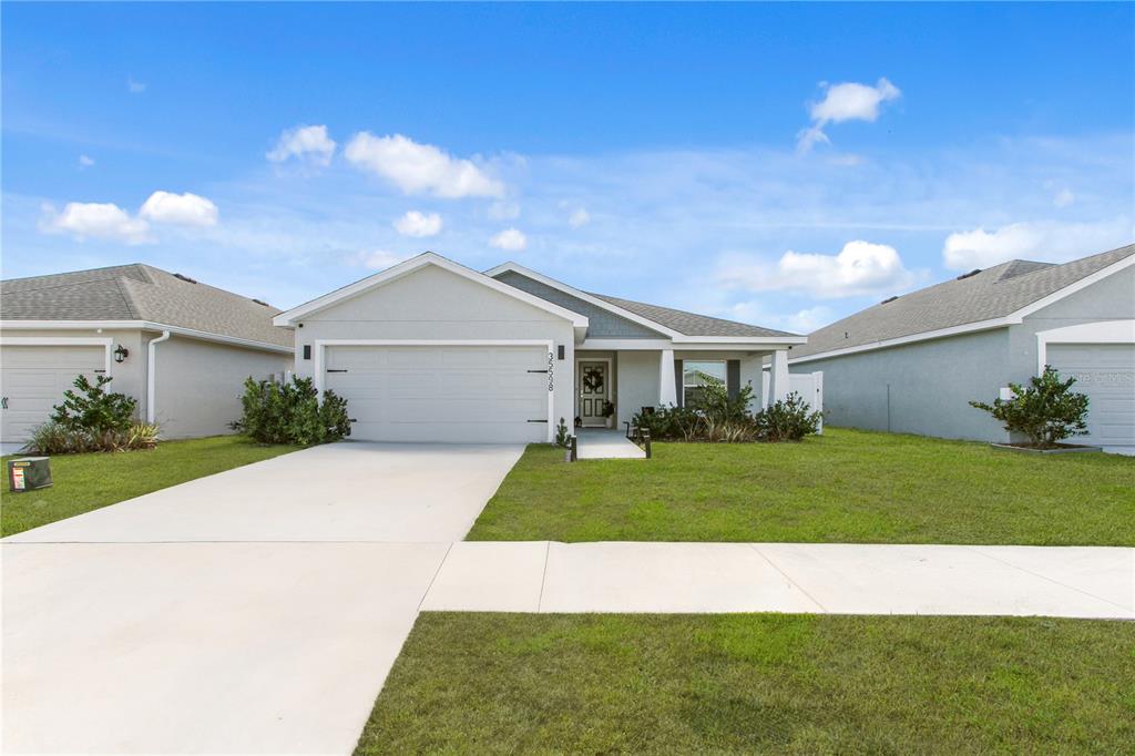 A single-story suburban house with a two-car garage, light gray exterior, and a front porch — 35598 BELLINGTON BOULEVARD, ZEPHYRHILLS, FL