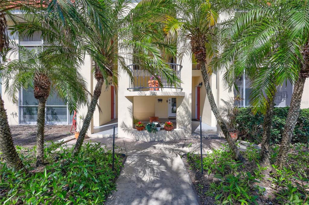 A concrete walkway leads to the entrance of a multi-story building framed by palm trees — 137 AVENIDA MESSINA UNIT 3, SARASOTA, FL