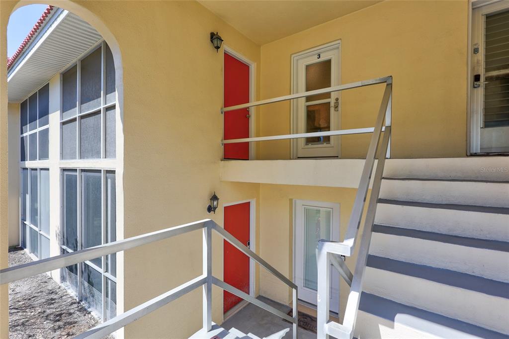 An exterior view of a two-story building with yellow stucco walls and metal staircases — 137 AVENIDA MESSINA UNIT 3, SARASOTA, FL