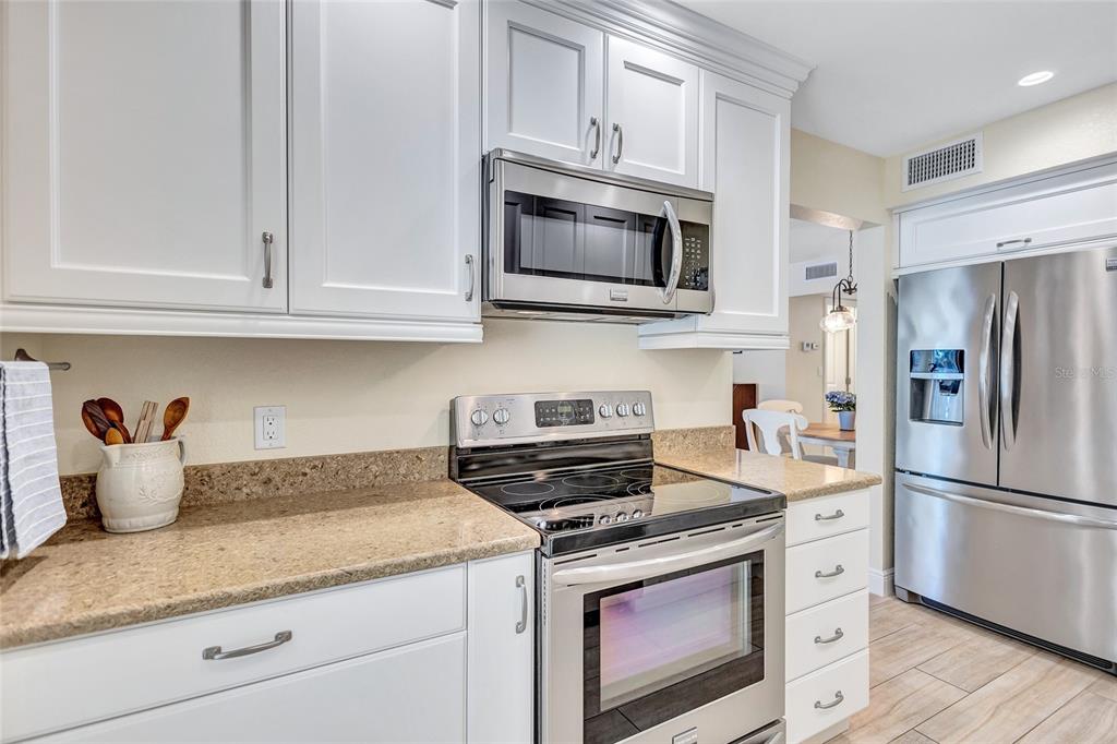 A kitchen features white cabinets, stainless steel appliances, and tan granite countertops — 137 AVENIDA MESSINA UNIT 3, SARASOTA, FL
