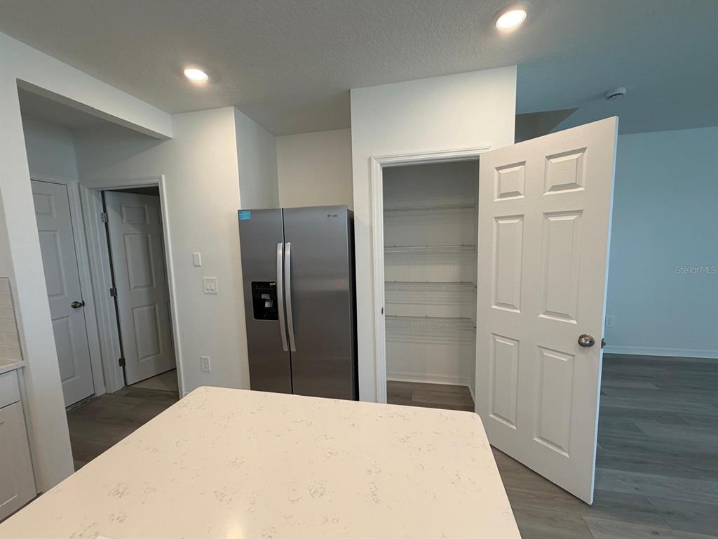 A kitchen features a stainless steel refrigerator, a pantry with wire shelving, and a countertop — 4264 RANCH HOUSE ROAD, ST CLOUD, FL