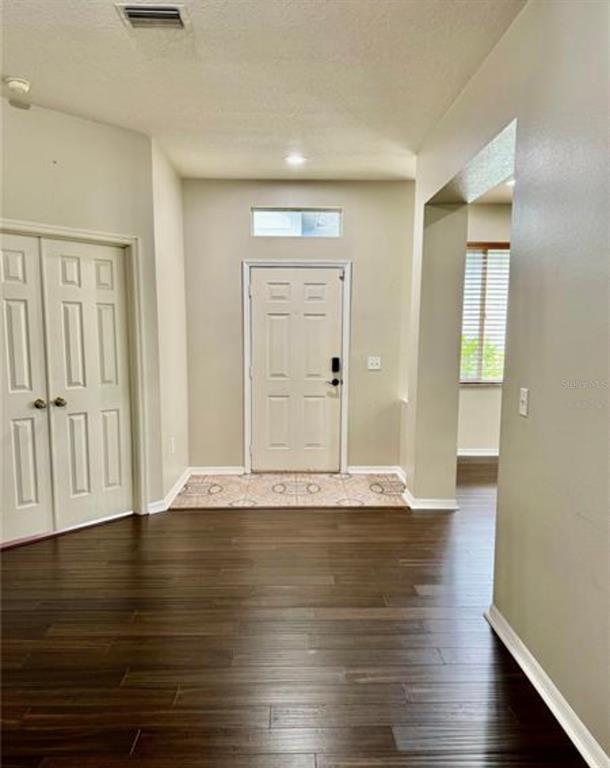 An entryway features dark wood-look flooring, a white front door, and a double-door closet — 30239 EMMETTS COURT, WESLEY CHAPEL, FL