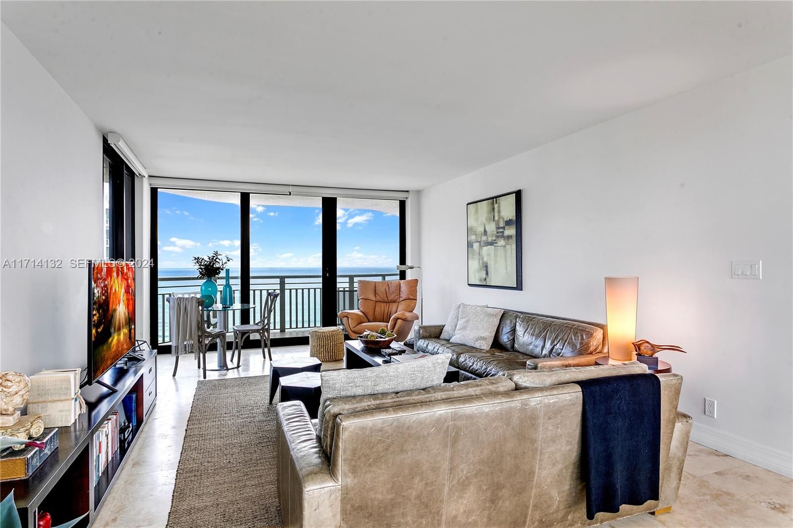 A living room features leather sofas, a television, and a balcony overlooking the ocean — 3000 N Ocean Dr # 20A, Riviera Beach FL 33404, RIVIERA BEACH, FL