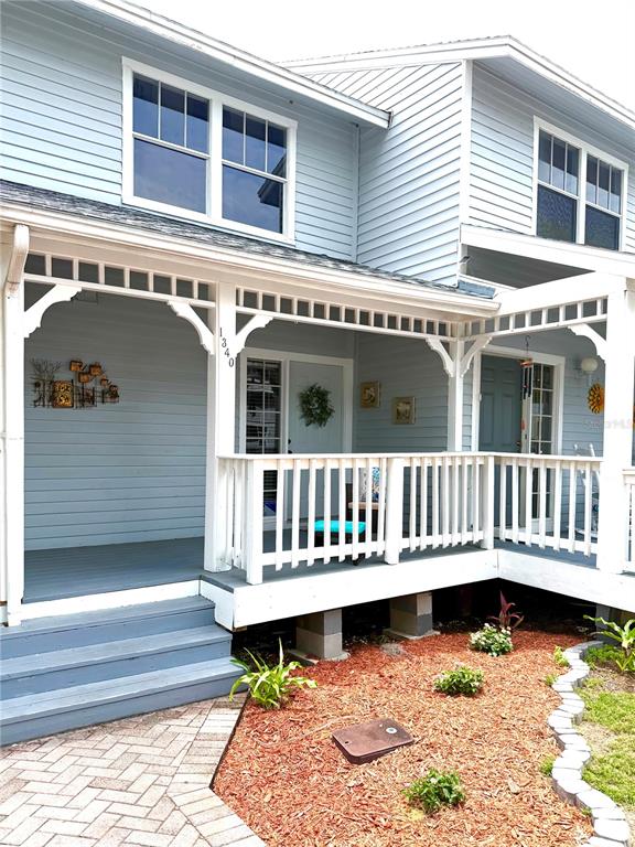 A light blue house features a covered front porch with white railings and wooden stairs — 1340 CYPRESS COVE COURT, INVERNESS, FL
