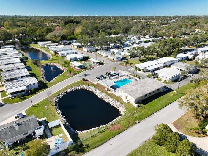 An aerial view shows a residential community with mobile homes, a swimming pool, and ponds — 2331 BELLEAIR ROAD UNIT 116, CLEARWATER, FL
