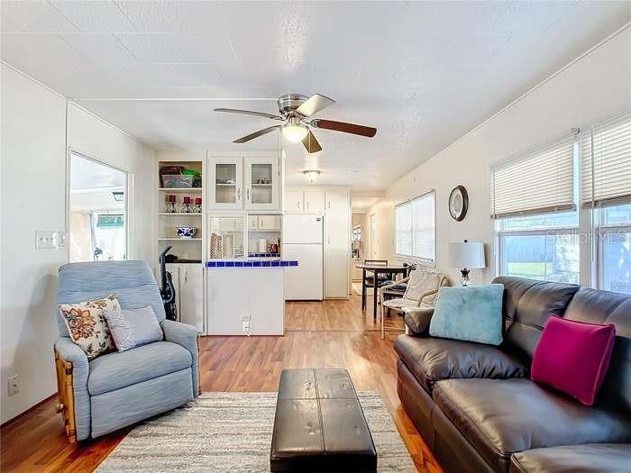 A living room features a blue recliner, a dark leather sofa, and an open kitchen — 2331 BELLEAIR ROAD UNIT 116, CLEARWATER, FL