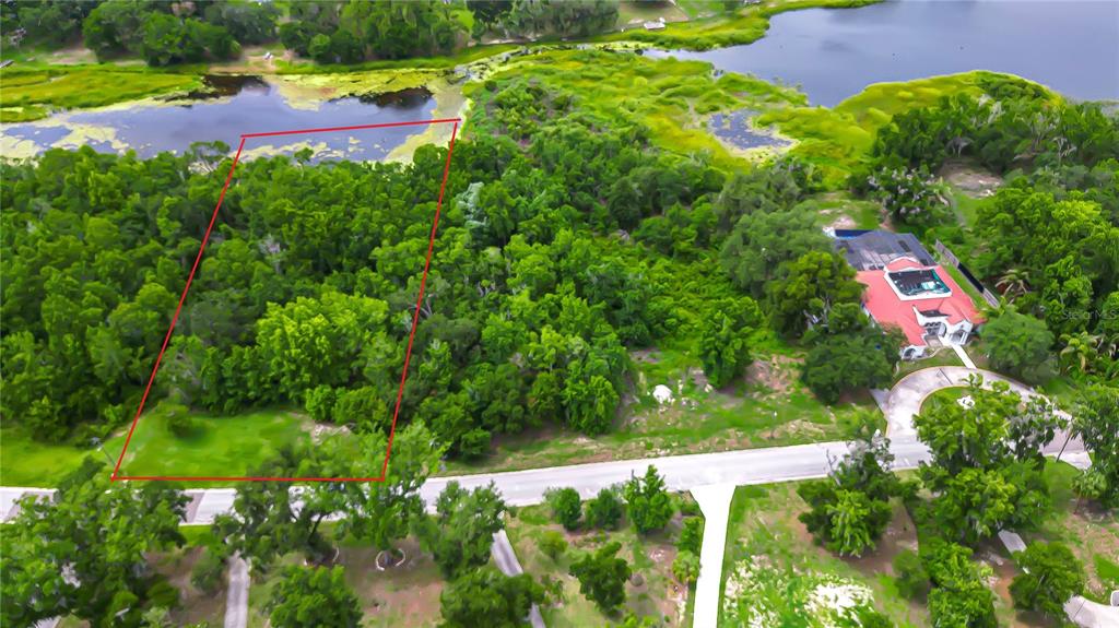 An aerial view shows a wooded lot outlined in red next to a waterfront house — LAKE HILLS DRIVE, RIVERVIEW, FL