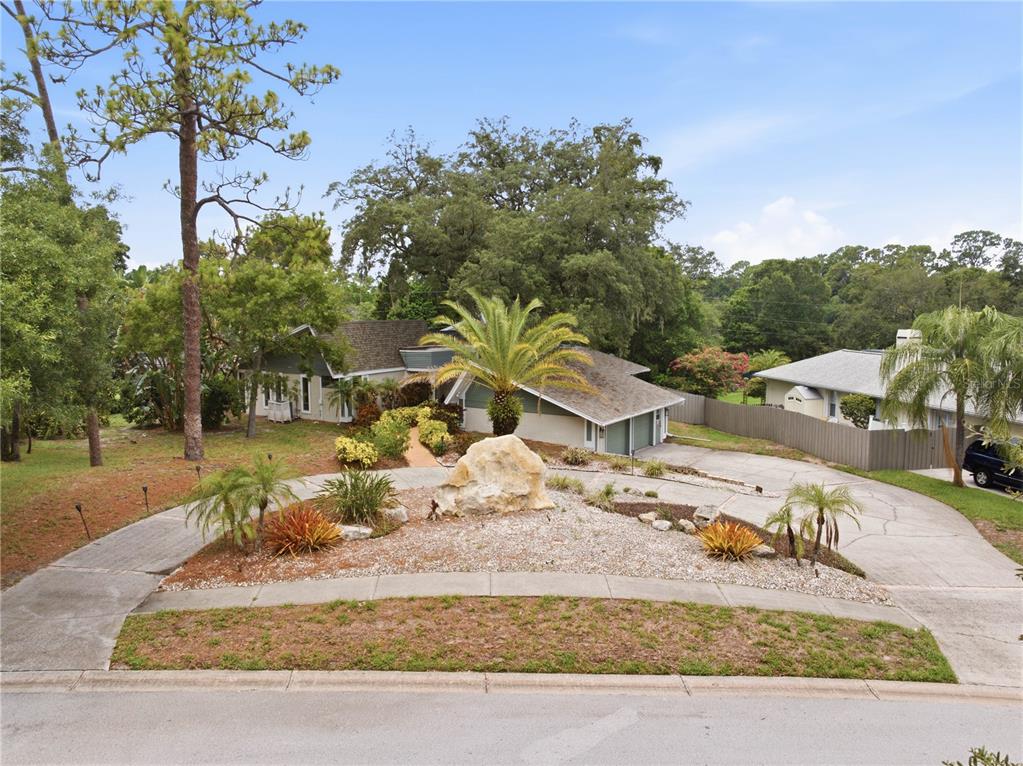 A split-driveway leads to a single-story house with a large rock in the front yard — 2860 BRIARWOOD LANE, PALM HARBOR, FL