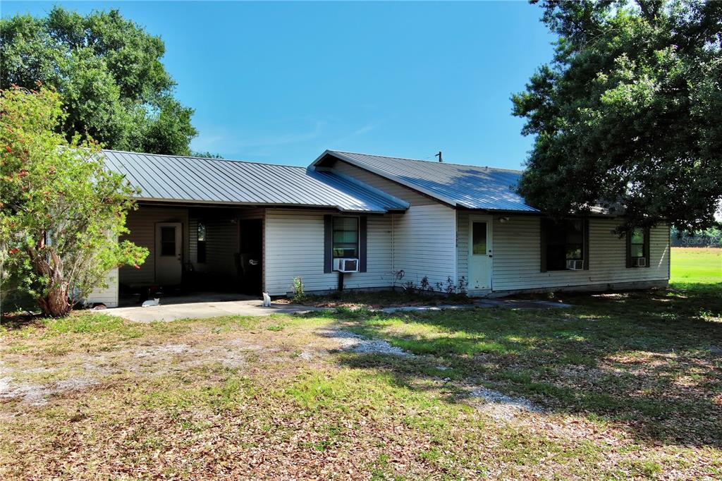 A single-story house with light siding, a metal roof, and an attached carport — 15610 STATE ROAD 62, PARRISH, FL