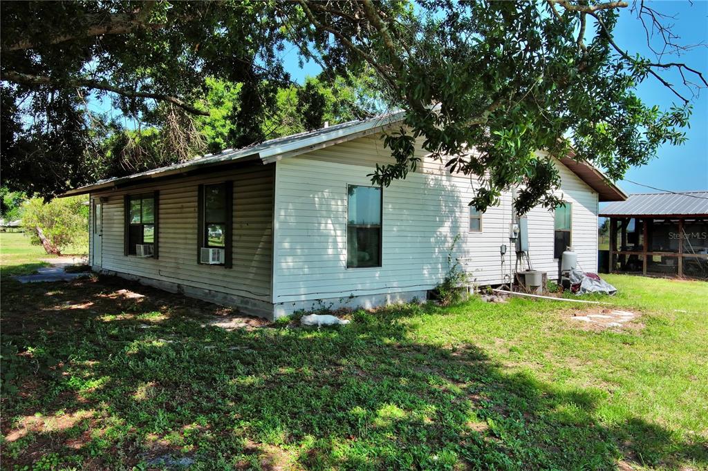 A single-story house with white horizontal siding and a metal roof stands on grass — 15610 STATE ROAD 62, PARRISH, FL