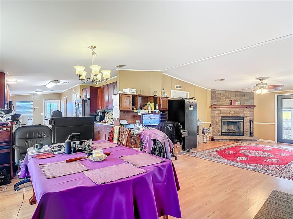 A living room and dining area feature a stone fireplace, wood flooring, and a purple-clothed table — 45750 PINE STREET, PAISLEY, FL