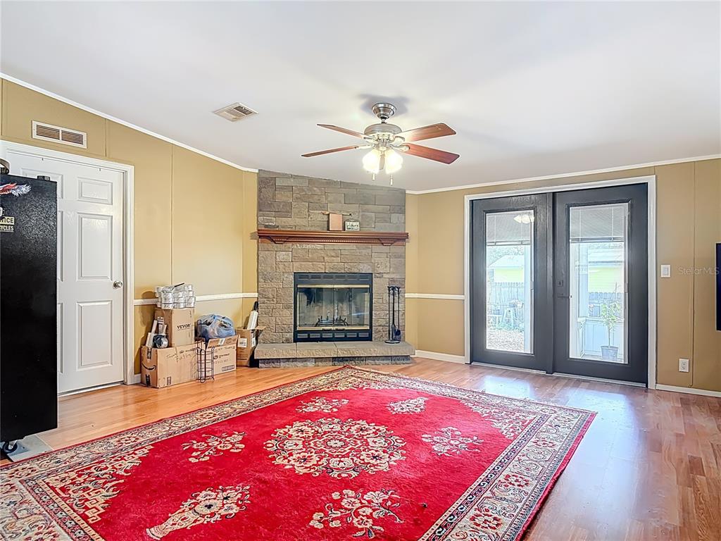 A living room features a stone fireplace, a red area rug, and dark glass doors — 45750 PINE STREET, PAISLEY, FL
