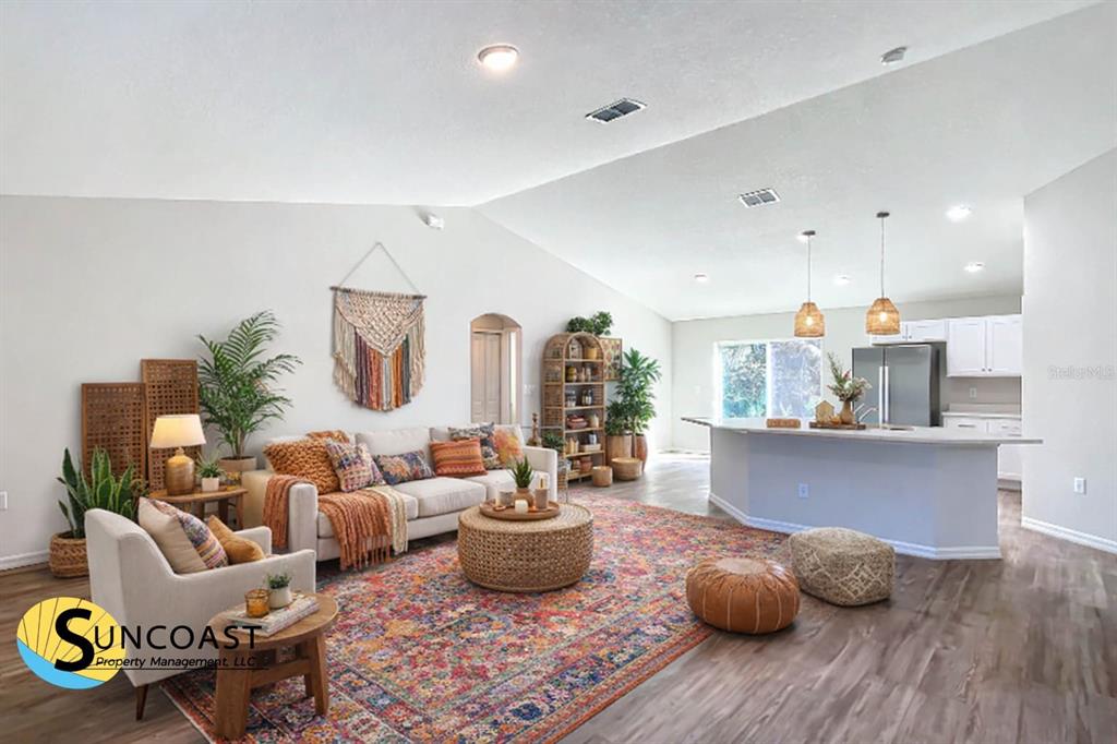 An open-concept living room and kitchen featuring wood-look flooring and a large area rug — 7850 SW 128TH STREET, OCALA, FL