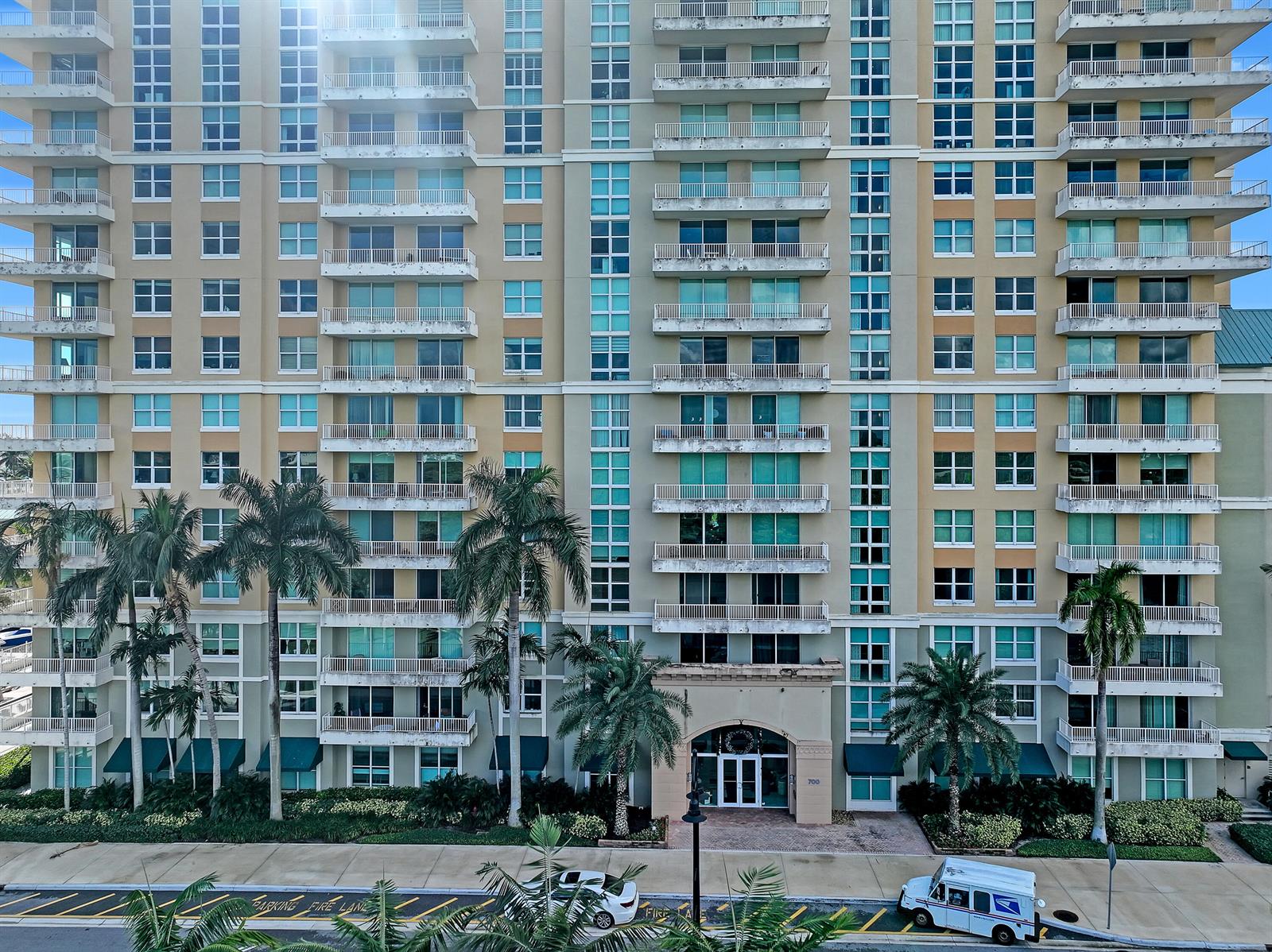 A multi-story residential building features balconies, large windows, and palm trees at the entrance — 700 E Boynton Beach Boulevard # 312, Boynton Beach FL 33435, BOYNTON BEACH, FL